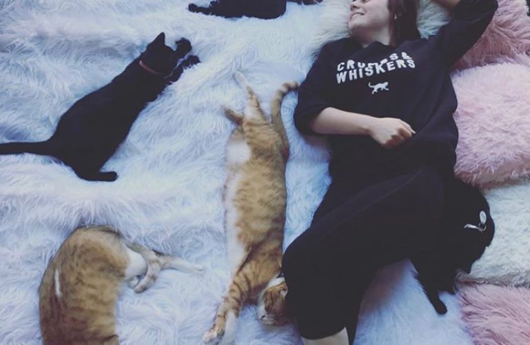 A woman lies on the carpet with cats at the Crumbs & Whiskers, Washington DC 