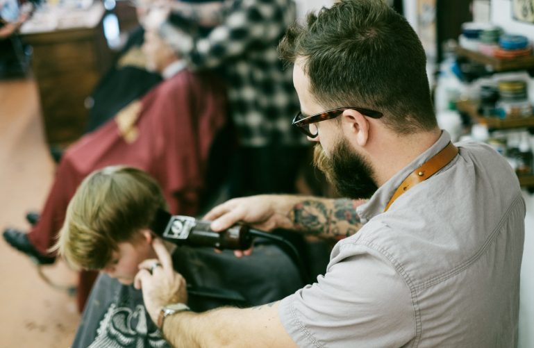 A man with tatoo is doing the haircut